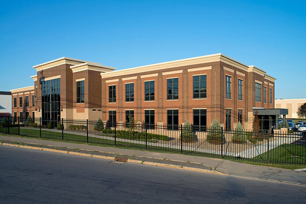 Brick building with lots of windows and a black fence around it